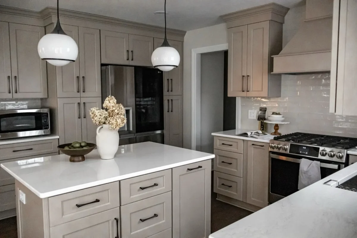 Bright modern kitchen with gray cabinets, white countertops, and two globe pendant lights over an island.